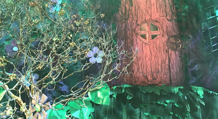 Scenekulisser av en skog med et stort tre i bakgrunnen, med et rundt vindu i stammen.