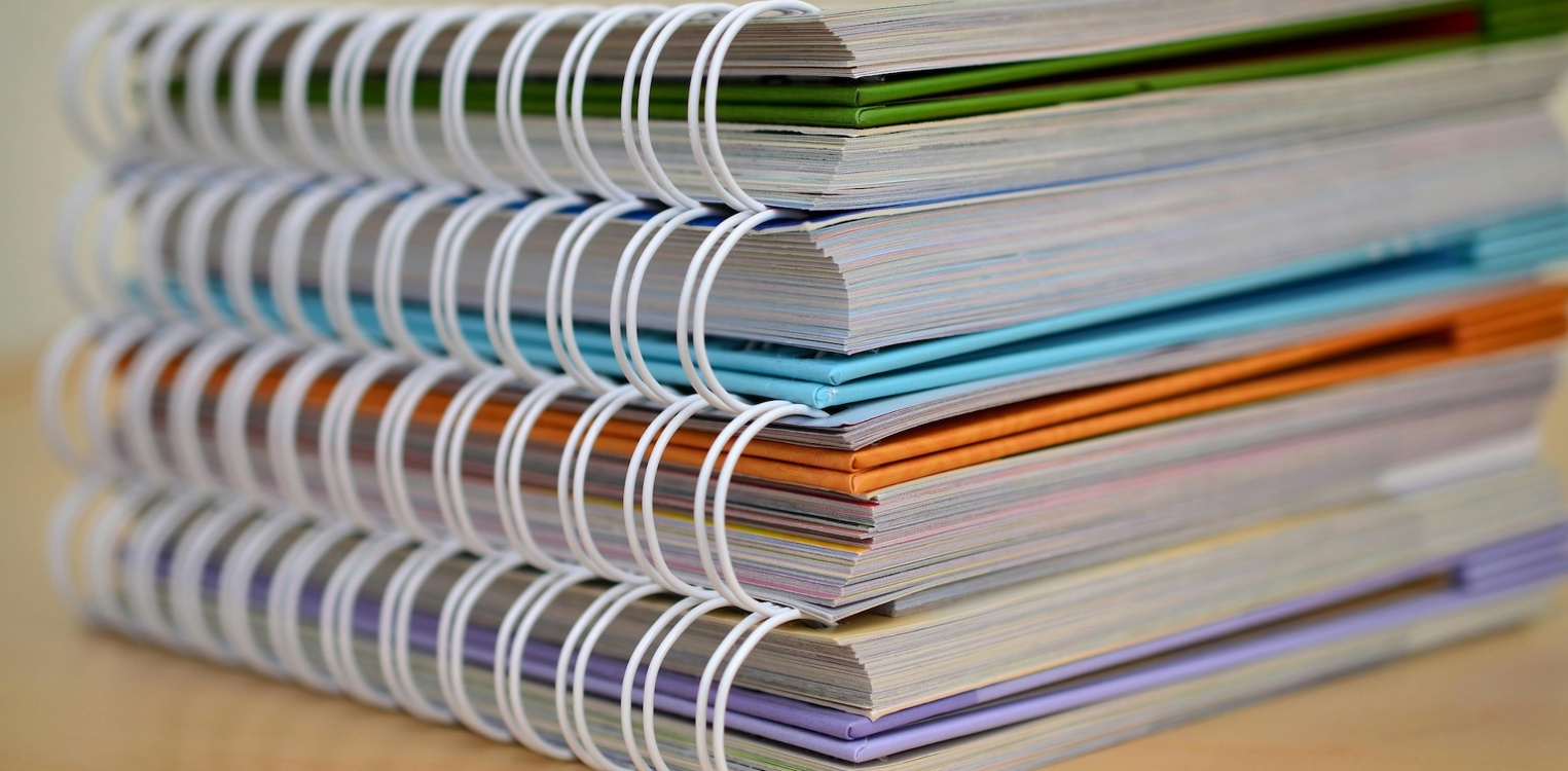 Fire spiralbundne notatblokker ligger stablet oppå hverandre. Bilde av Pixabay: https://www.pexels.com/nb-no/bilde/boker-skole-fargerik-ringer-272980/