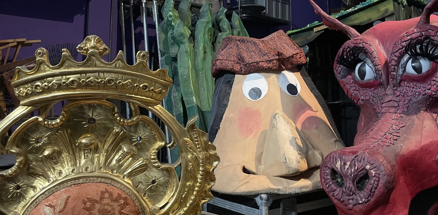 Kulisselager hos Frilynt med gullstol, stort ansikt og Shrek-dragen plassert på flightkasser blant ulike rekvisitter.