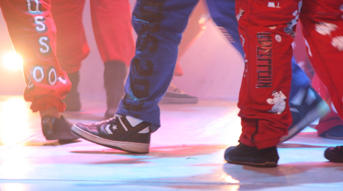 Russ i blå og røde bukser går på scenen; vi ser bare bukseben og sko.