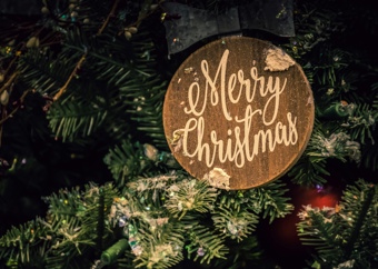 Julepynt med teksten «Merry Christmas» hengende på et juletre.