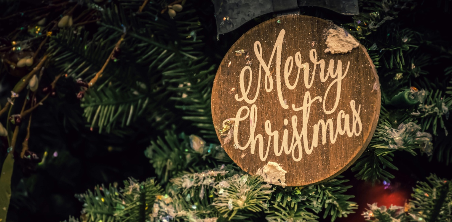 Julepynt med teksten «Merry Christmas» hengende på et juletre.