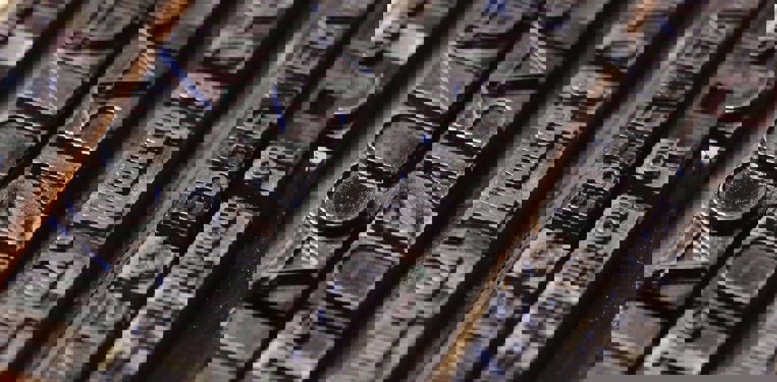 En tradisjonell trykkemekanisme vises med metallbokstaver plassert i rader. Detaljene fremhever håndverket bak eldre trykkteknikk og gir et historisk preg.